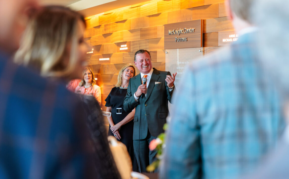 Joe Eastin speaking to a small group near a backdrop