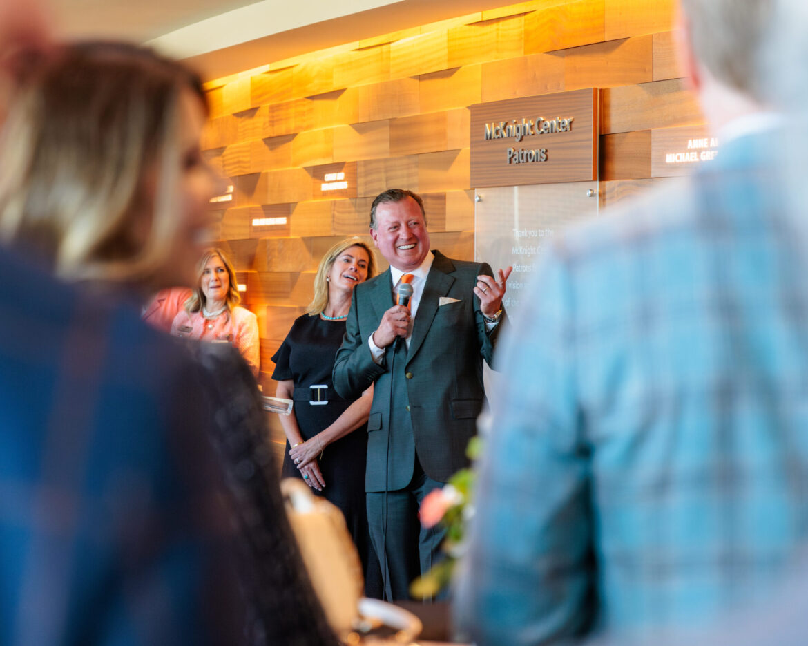 Joe Eastin speaking to a small group near a backdrop