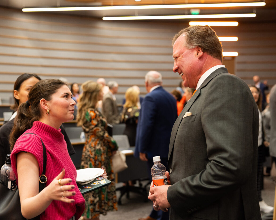 Joe Eastin speaking with two attendees at a social event