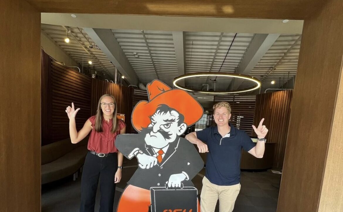 Two students posing with an OSU mascot cutout at an event