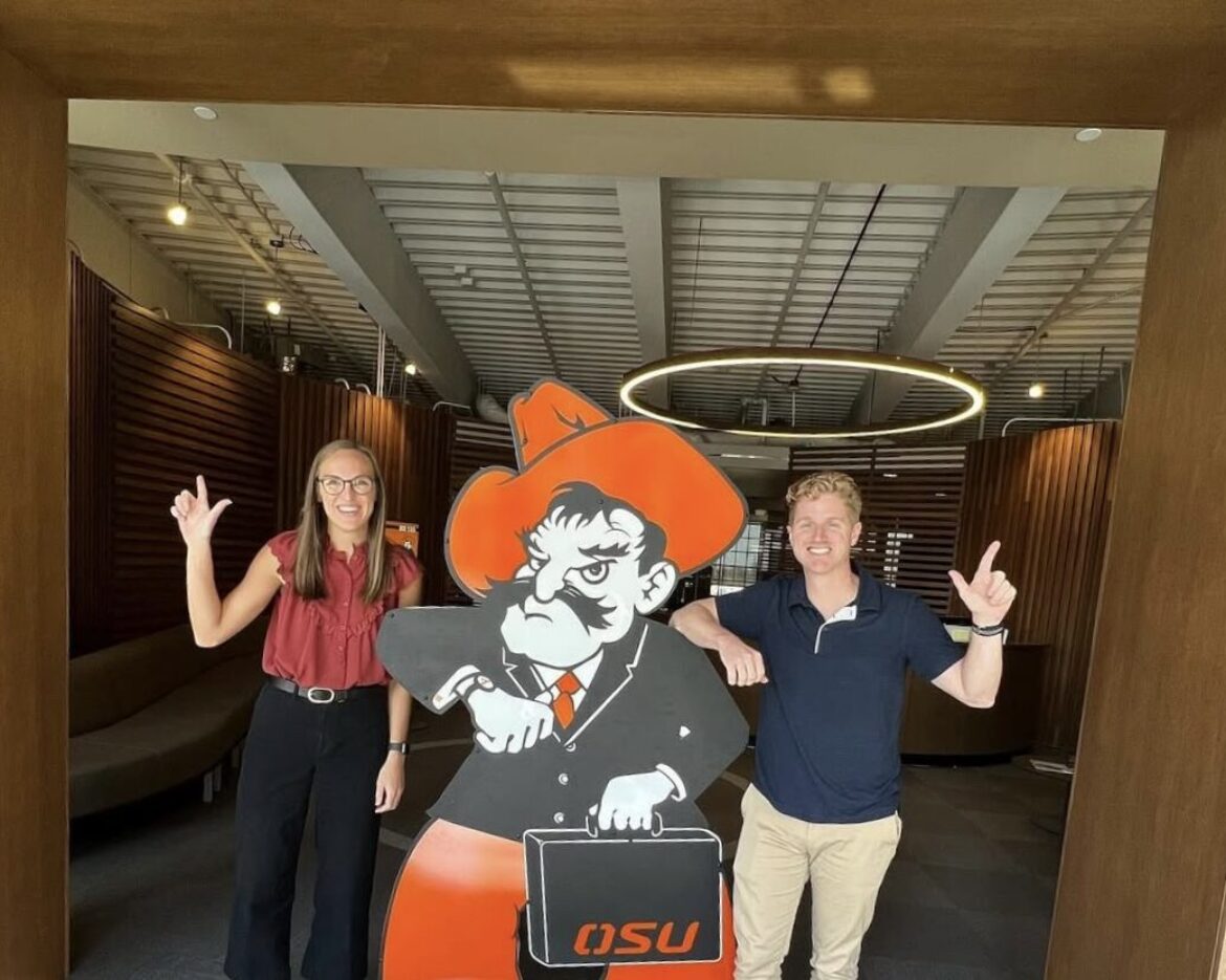 Two students posing with an OSU mascot cutout at an event