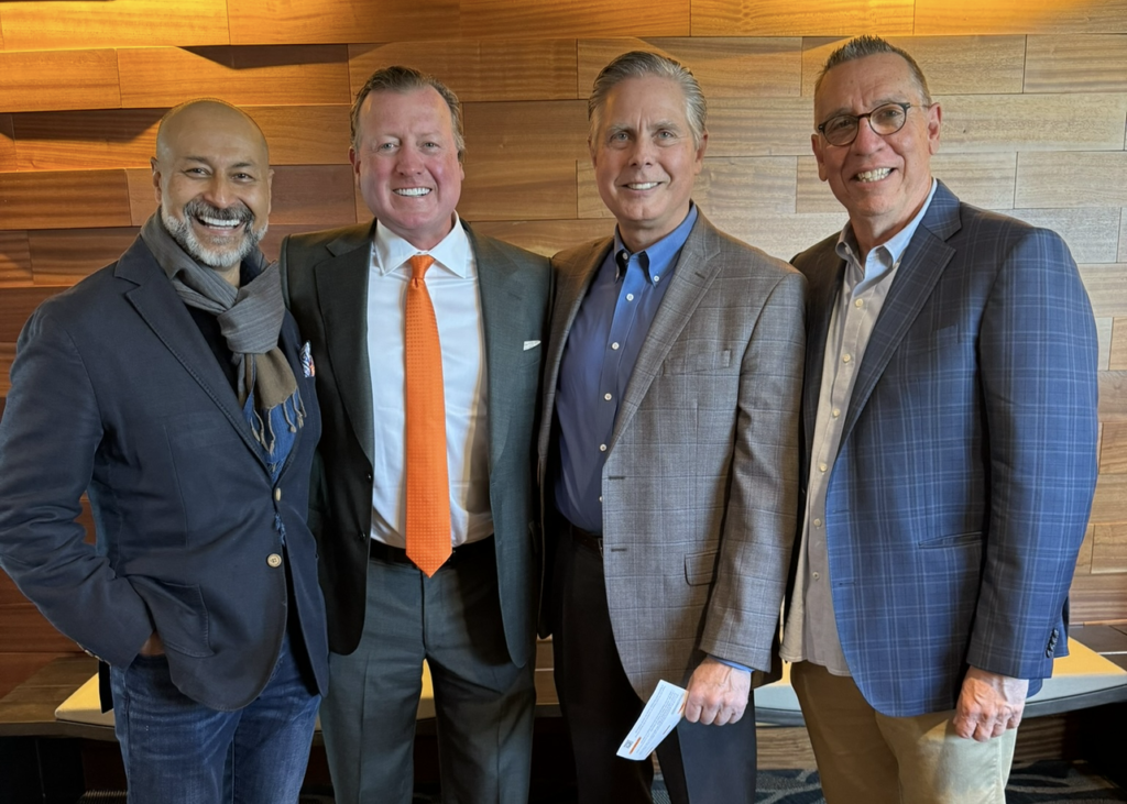 Joe Eastin standing with three male attendees at an event