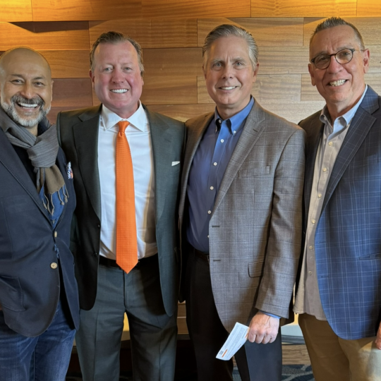Joe Eastin standing with three male attendees at an event